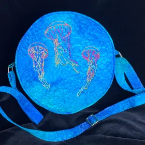 Picture of a circular blue handbag with colorful jellyfish embroidered on the front